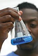 Researcher holding up a blue solution