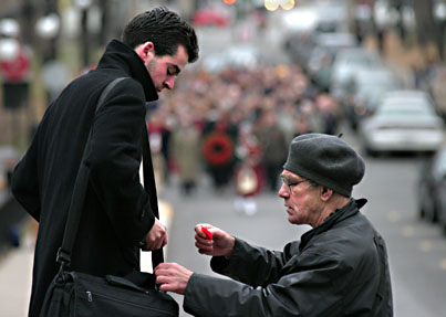 A veteran pins a poppy on a McGill student's bag