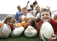 A group of children pose with rugby balls